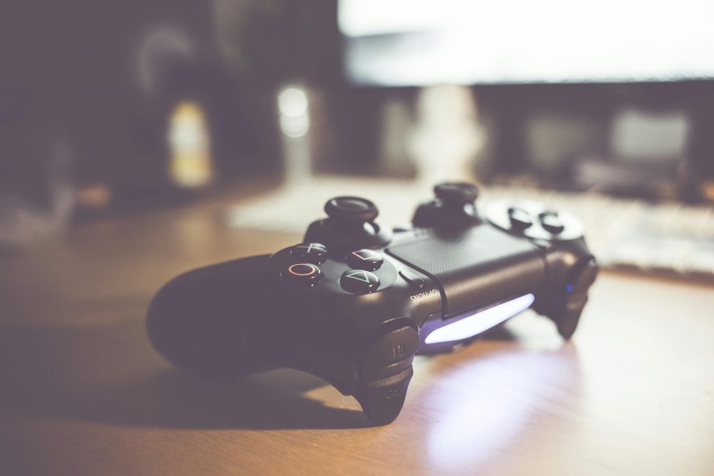 A stylish gaming controller placed on a wooden desk with a warm lighting setup.